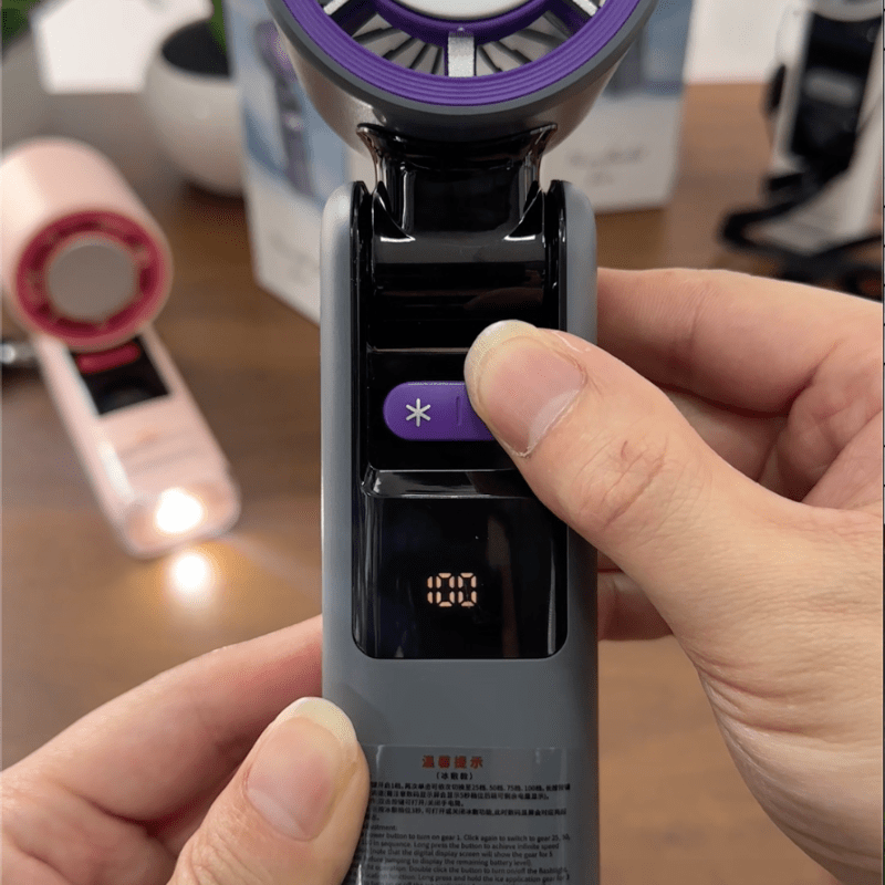 User pressing the cooling button on a handheld turbo fan with digital screen displaying speed level, highlighting control interface and ease of use - techynook