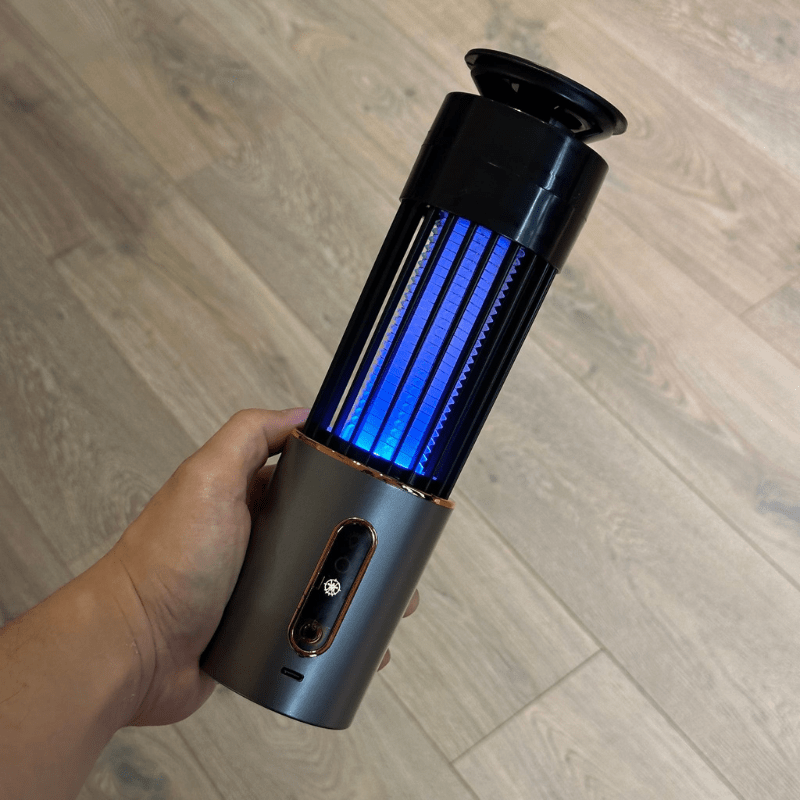 Hand holding portable mosquito zapper with UV light. Rechargeable electric insect killer for indoor and outdoor mosquito control, chemical-free and efficient.
