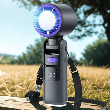 Handheld turbo fan with shoulder strap and digital display placed on a wooden bench in an outdoor field, designed for portable cooling during travel or summer activities - techynook